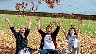 Group of students throw leaves into the air